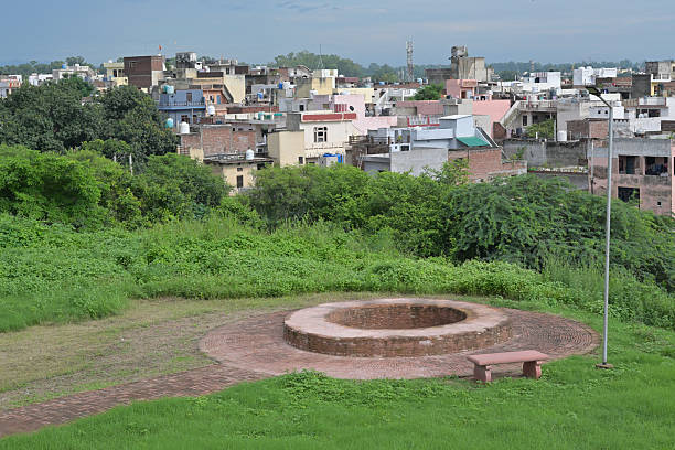 istock The image shows a circular brick structure surrounded by lush greenery and located in a cityscape with numerous low-rise buildings in the background. 2231151345