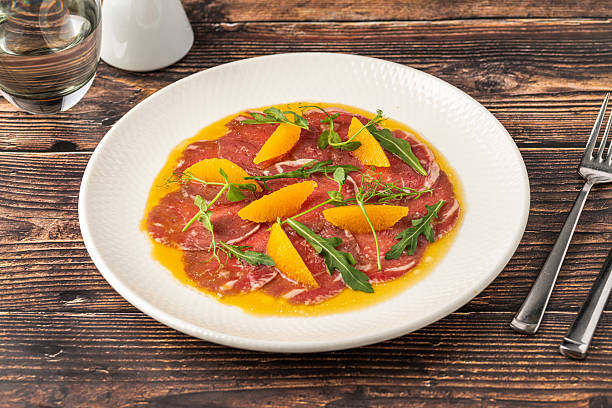 istock Thinly sliced beef carpaccio with orange segments and arugula leaves 2231153925