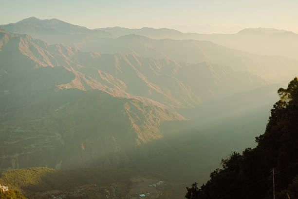 A breath taking view of layered mountain ranges covered in soft morning mist, bathed in golden sunlight. The serene atmosphere highlights the beauty of untouched nature, ideal for travel, landscape, and nature concepts.
