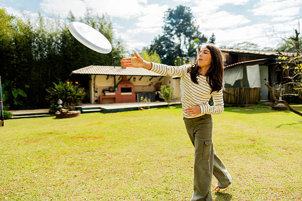 Girl playing throwing plastic disc in the backyard at home