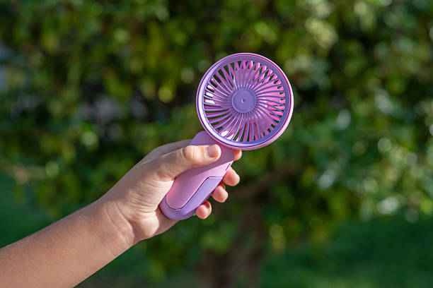 istock Hand holding portable mini fan outdoors in sunlight 2231160903