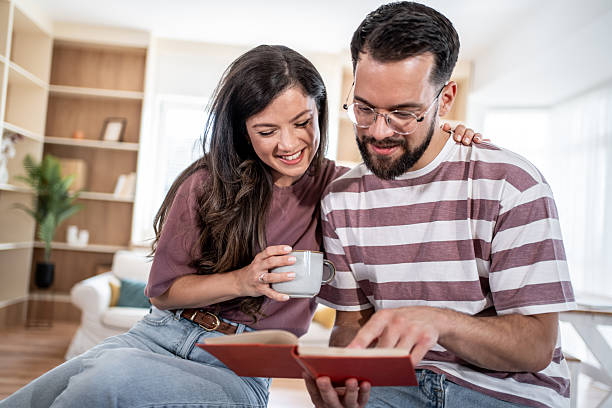 istock Young couple reading a book and drinking coffee at home 2231162324