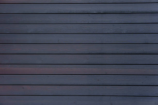 istock Dark wooden wall formed by horizontal planks with deep grain lines and subtle sheen. 2231163115