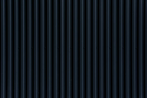istock Vertical ridges and grooves define a dark corrugated metal wall. 2231163274