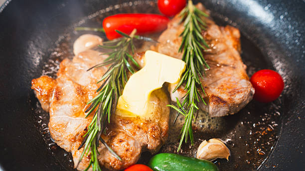 istock Pork Chops in Pan with Cherry Tomatoes, Peppers, and Rosemary 2231165688