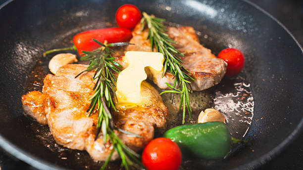 istock Pork Chops in Pan with Cherry Tomatoes, Peppers, and Rosemary 2231165703