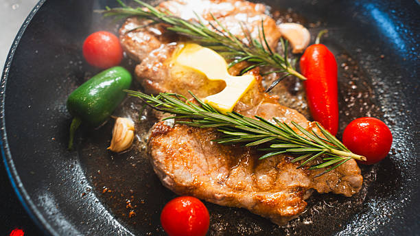 istock Pork Chops in Pan with Cherry Tomatoes, Peppers, and Rosemary 2231165707