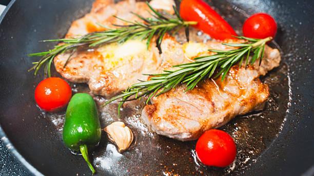 istock Pork Chops in Pan with Cherry Tomatoes, Peppers, and Rosemary 2231165715