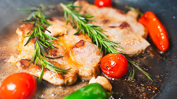 istock Pork Chops in Pan with Cherry Tomatoes, Peppers, and Rosemary 2231165721