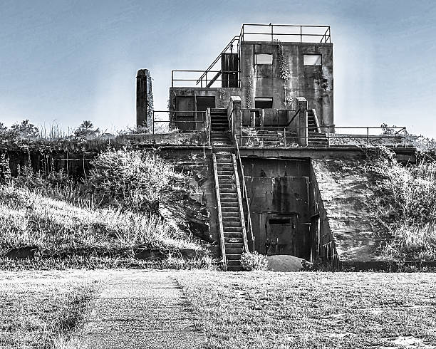 A haunting black-and-white image of a decaying coastal military bunker, believed to date back to World War II, stands as a silent monument to forgotten conflict and the relentless passage of time. Located along the Florida coastline, this abandoned fortification features weathered concrete, rusting railings, and staircases leading to a derelict observation post. Overgrown vegetation creeps across the structure, symbolizing nature’s quiet reclamation of man-made history.The stark monochrome palette enhances the mood of isolation and memory, making this image ideal for editorial use in historical retrospectives, environmental commentary, or conceptual design. Its cinematic composition and gritty textures also lend themselves to dystopian themes, post-conflict storytelling, and advocacy campaigns focused on preservation or military legacy.Perfect for book covers, magazine spreads, documentary visuals, and fine art prints, this photograph bridges the gap between historical documentation and emotional storytelling.