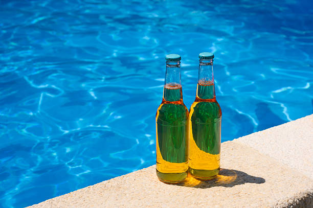 istock Two bottles of beer by the pool on a sunny day. 2231177457