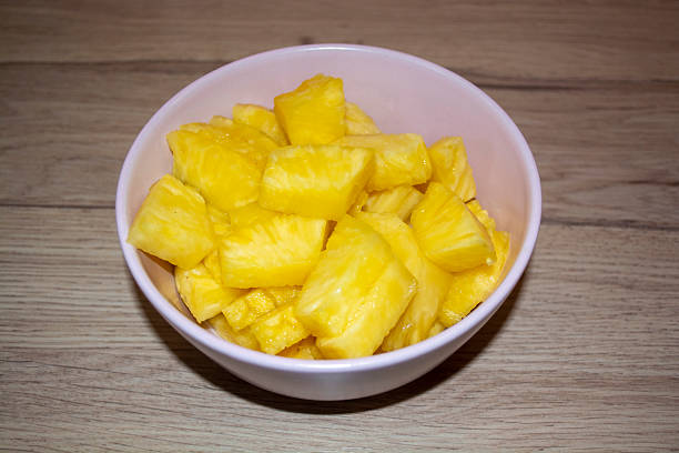 Photograph of ripe juicy pineapple cut into pieces and served in a pink bowl. Perfect for culinary photography, tropical fruit concepts, healthy eating, summer recipes, and refreshing dessert illustrations