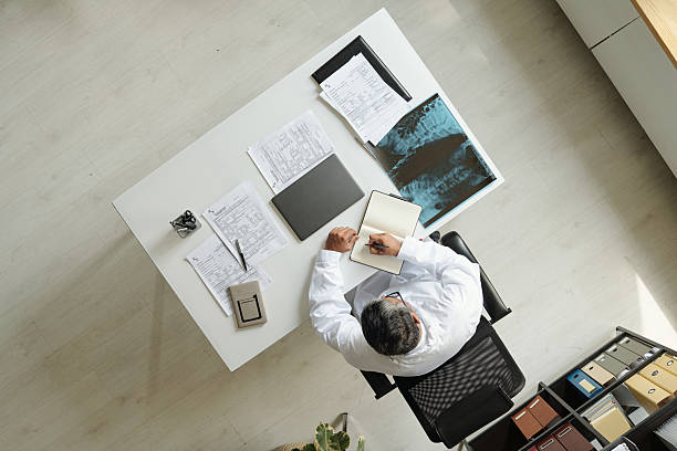istock Middle Aged Caucasian Man Doctor Reviewing X Ray Image and Taking Notes 2231181749