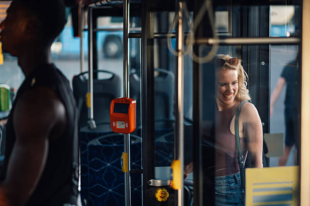 istock Young woman paying bus fare while smiling at ticket machine 2231181876