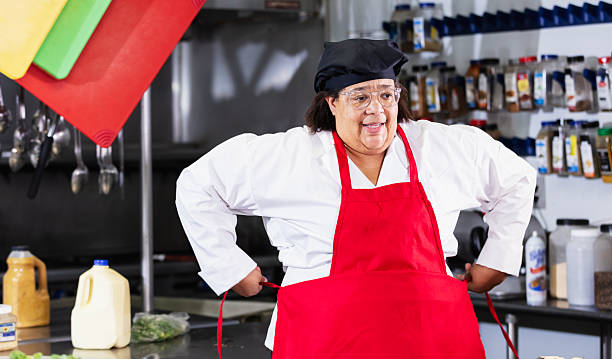 Female cook in commercial kitchen putting on apron