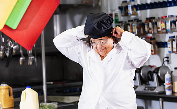 istock Female cook in commercial kitchen putting on hat 2231182294