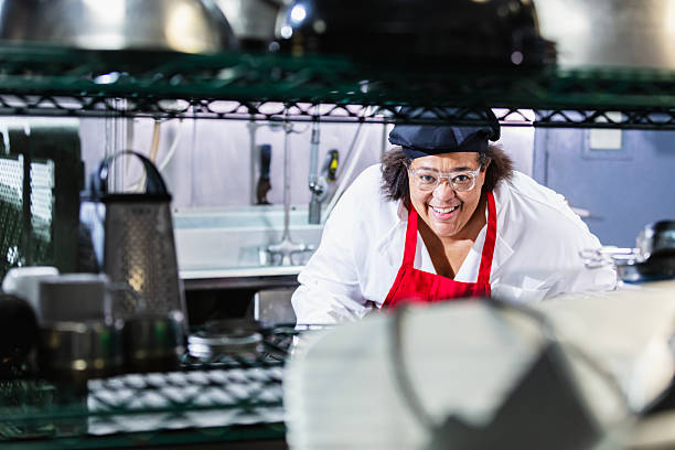 istock Black woman chef in restaurant kitchen smiling at camera 2231182424