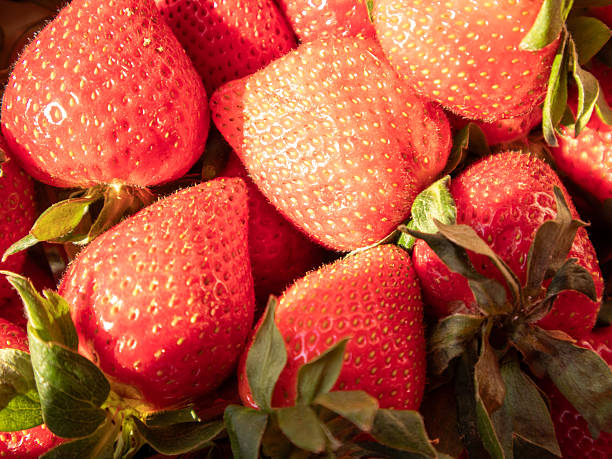 Fresh Red Strawberries Piled Together in a Vibrant Display, Showcasing Their Juicy Texture and Green Leaves