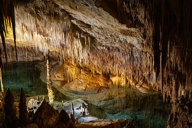 istock Stunning stalactite cave with reflective pool and warm glow 2231185297