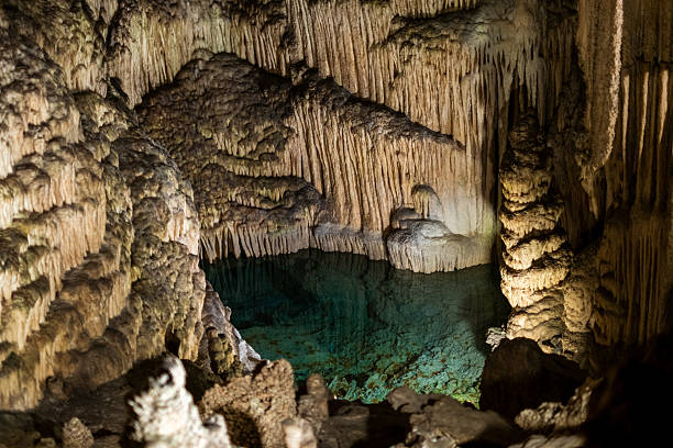 Majestic stalactites and stalagmites in illuminated underground cave pool.