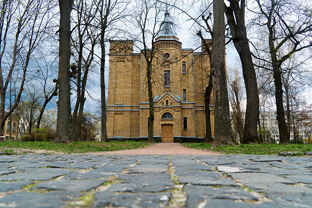 istock An old brick building framed by trees, with a cobblestone path 2231189989