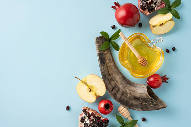 istock Flat lay composition featuring symbols of Rosh Hashanah including honey, apples, pomegranate, and a shofar on a pastel blue background 2231193401