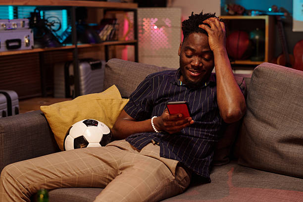istock Young Adult Black Man Smiling While Reading Message on Smartphone Indoors 2231193665
