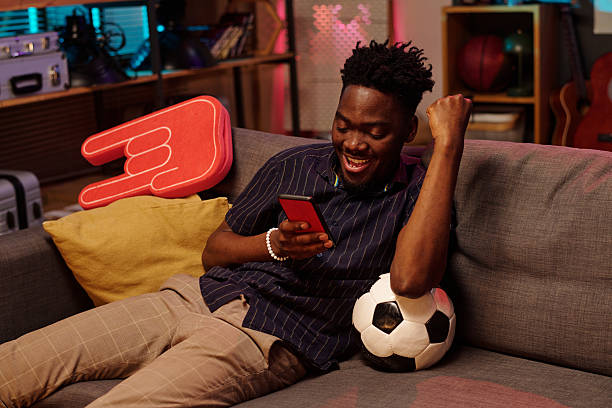 istock Young Adult Black Man Celebrating Victory While Using Smartphone Indoors 2231193666
