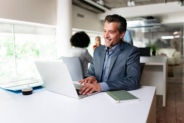 istock Smiling businessman working on laptop in modern office 2231193776