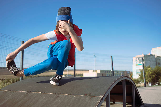 istock Young boy having fun and practicing breakdance on skate ramp 2231201495