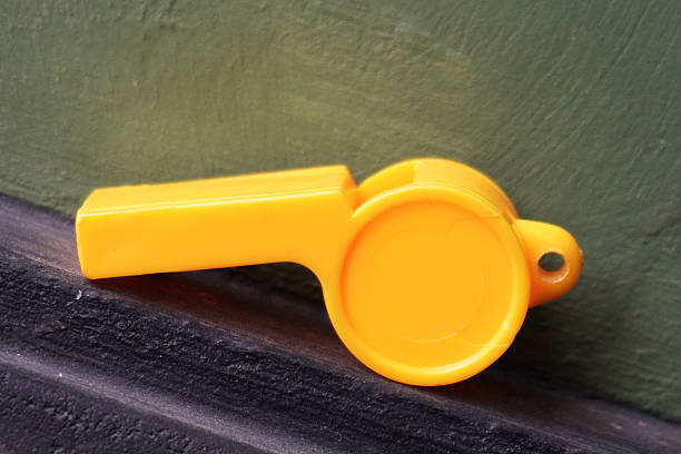 Metal whistle on a white background. Whistle with a shadow close-up.