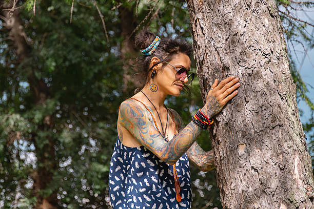 Woman stands next to tree, touching its bark, finding peace and connection with nature in outdoor therapy.