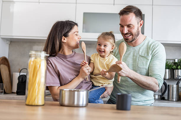 istock Happy family playing with wooden spoons while cooking in kitchen 2231203132