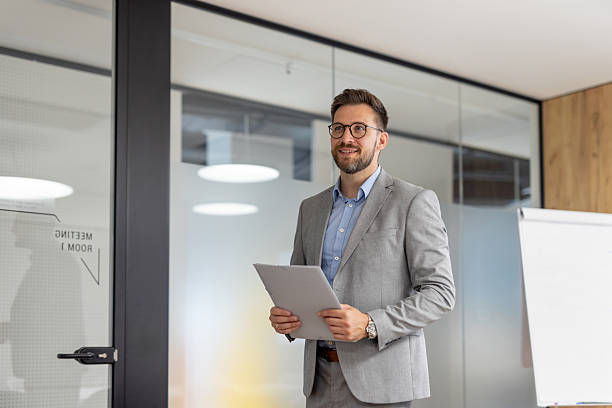 istock Businessman holding documents and smiling in modern office 2231203612