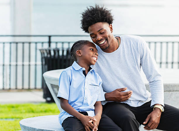 istock Young man and nephew sitting by city waterfront 2231207319
