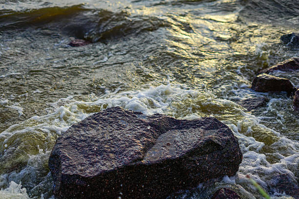 Waves crashing on rocky shore at sunset