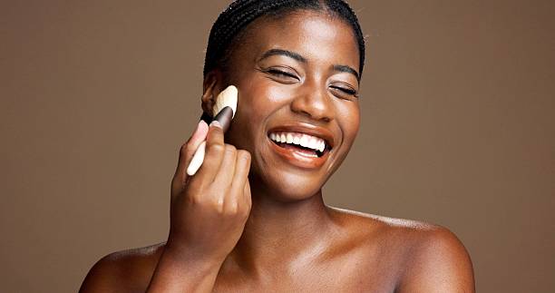istock Makeup, brush and smile with black woman in studio for foundation application, glow and self care. Beauty tools, cosmetics and shine with female person on brown background space for blush powder 2231210812
