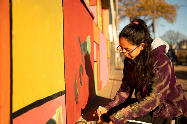 istock Young non-binary artist painting its artwork on a mural 2231215411