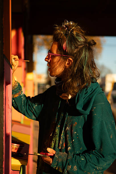 Young non-binary artist painting its artwork on a mural - Buenos Aires - Argentina