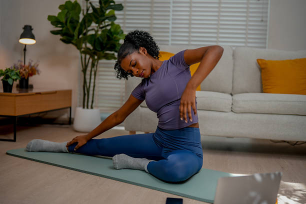 istock Black female engages in indoor exercise by practicing yoga, stretching gracefully on mat in serene living space filled with natural light and greenery 2231230651