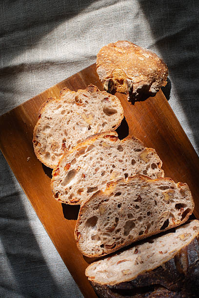 cranberry walnuts sourdough bread sliced placed on wooden cutting board.