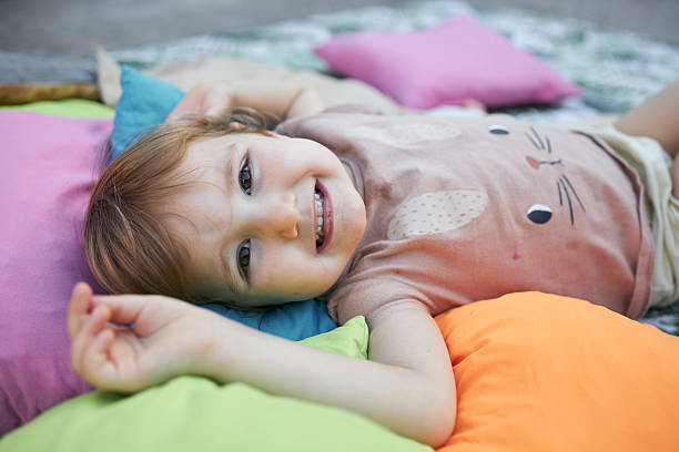 Happy smiling girl on the floor with blanket and pillows.