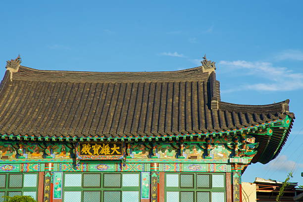 Haewoon Temple's Daeungbojeon hall with dancheong-painted eaves and tiled giwa roof in late afternoon light, the calligraphy signboard hanging above green lattice windows at Gwideok Village.