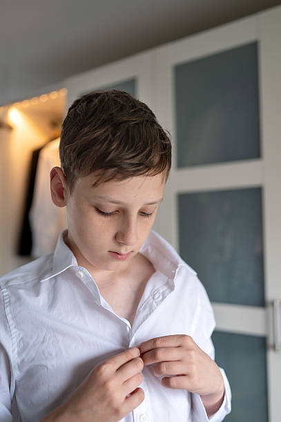 istock Schoolboy fastening shirt buttons before school. Back to school. 2231248733