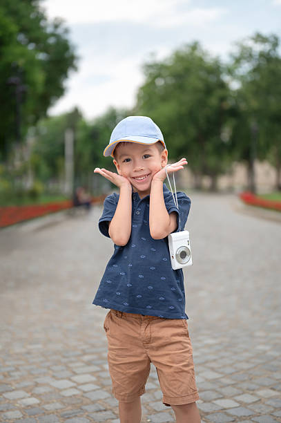 Headshot portrait of a cute happy white Caucasian boy wearing a baseball cap, smiling and looking directly at the camera
