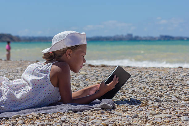 istock Child immersed in a book at the beach 2231254895