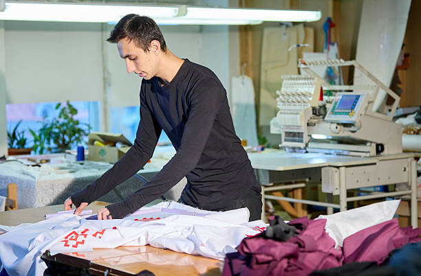 istock A tailor laying out white fabric with red traditional ornament on a table 2231259946