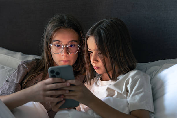 istock Two girls in bed. Smartphone screen. Evening cozy mood 2231265130