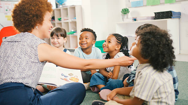 istock Female Teacher Reads And Asks Questions To Multi-Cultural Elementary School Pupils In Class 2231269006