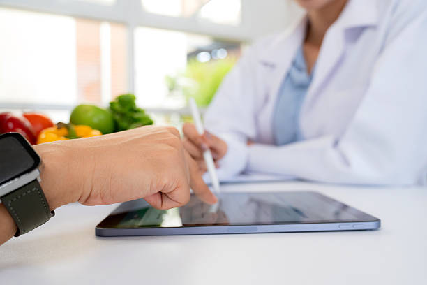 istock Asian nutritionist using tablet to explaining personalized meal plan with AI to patient during healthcare consultation, healthy lifestyle, woman dietitian showing nutrition plan with AI on tablet. 2231271272